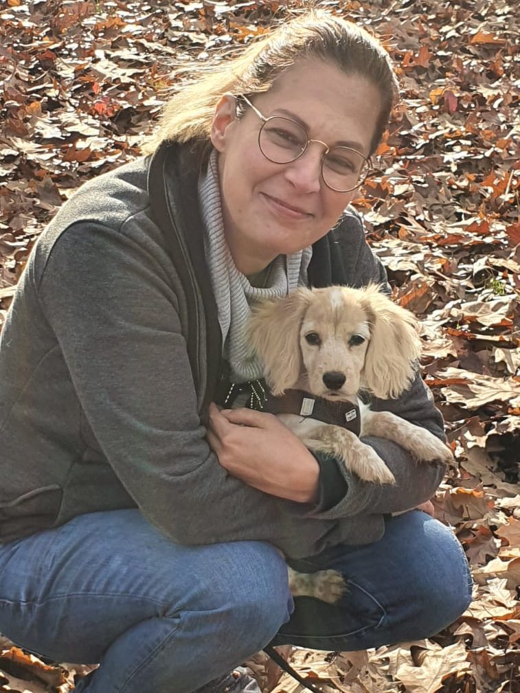 Stephanie Labes hält Hundewelpen in Duisburg im Arm und geht dabei in die Hocke. 