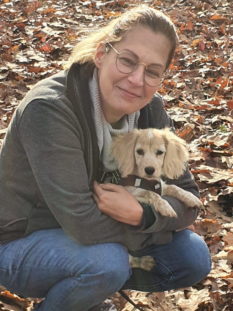 Stephanie Labes hält Hundewelpen in Duisburg im Arm und geht dabei in die Hocke.